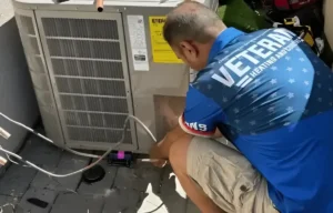 A man squatting while inspecting an AC system